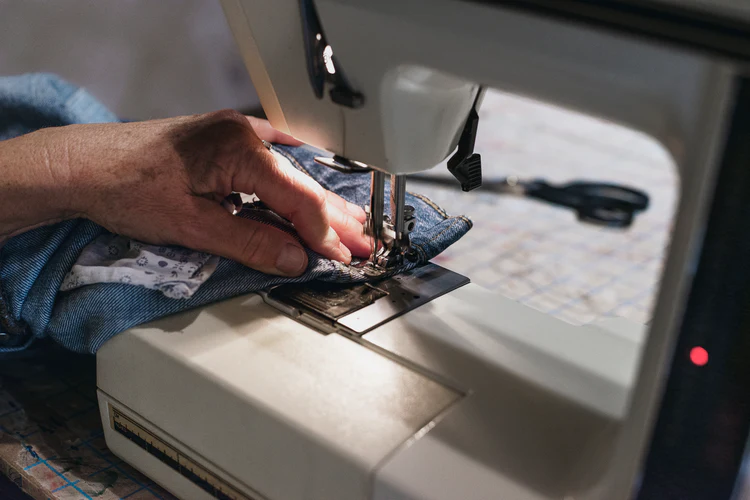 hands-guiding-demin-on-sewing-machine